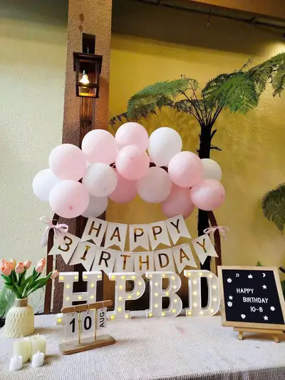 Trang trí tông hồng trắng: bóng bay, băng chữ Happy Birthday, chữ HPBD và bảng đen viết tên