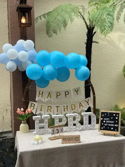 Trang trí tông xanh trắng: bóng bay, băng chữ Happy Birthday, chữ HPBD và bảng đen viết tên