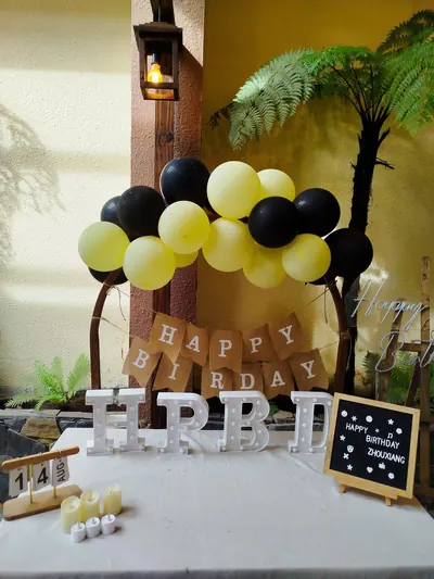 Trang trí tông vàng đen: bóng bay, băng chữ Happy Birthday, chữ HPBD và bảng đen viết tên
