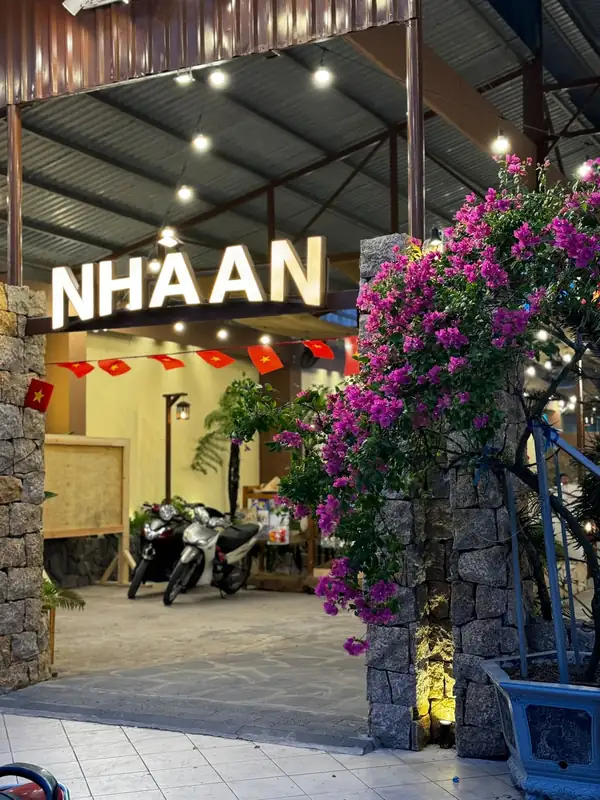 Cổng vào buổi tối, biển NHÀ AN sáng đèn giữa giàn hoa giấy