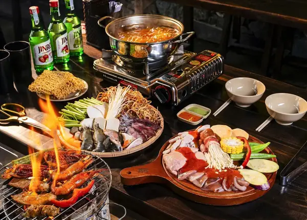 Nồi lẩu đang sôi trên bếp lửa giữa bàn